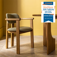 Dining chair with wooden frame and green cushion next to a wooden table against a yellow wall, with an award badge for 'Best Dining Chair' displayed.